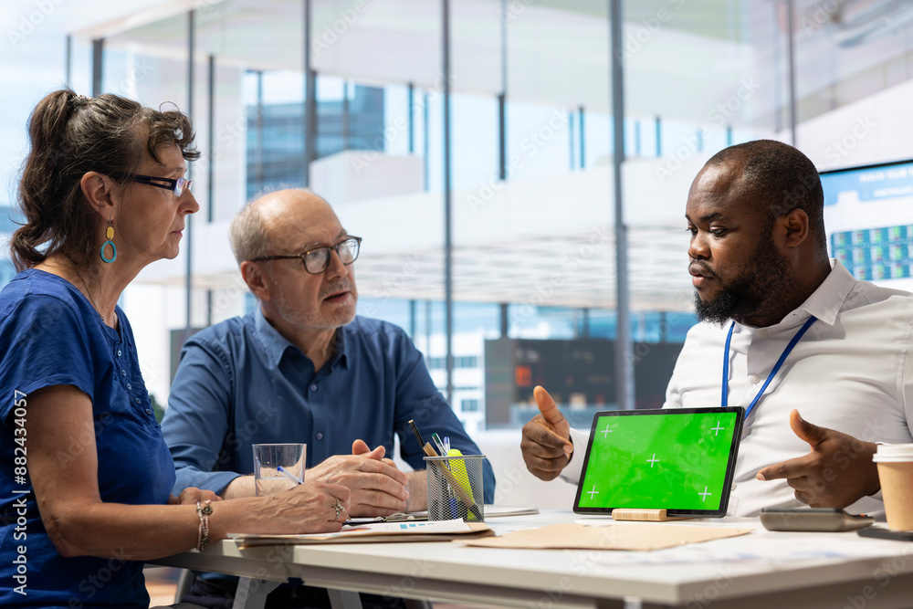 Financial banker works with a copy space on tablet with his elderly clients, showcasing retirement plans and pension options to secure their income and life savings. Insurance agency.