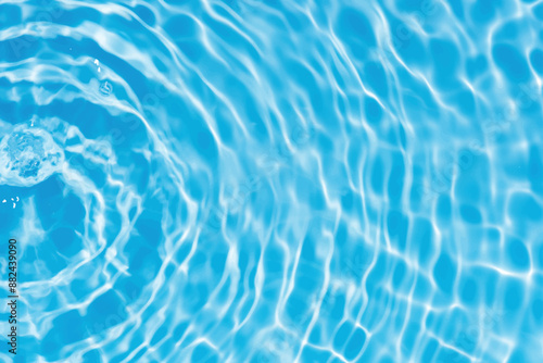 Blue water with ripples on the surface. Defocus blurred transparent blue colored clear calm water surface texture with splashes and bubbles. Water waves with shining pattern texture background.