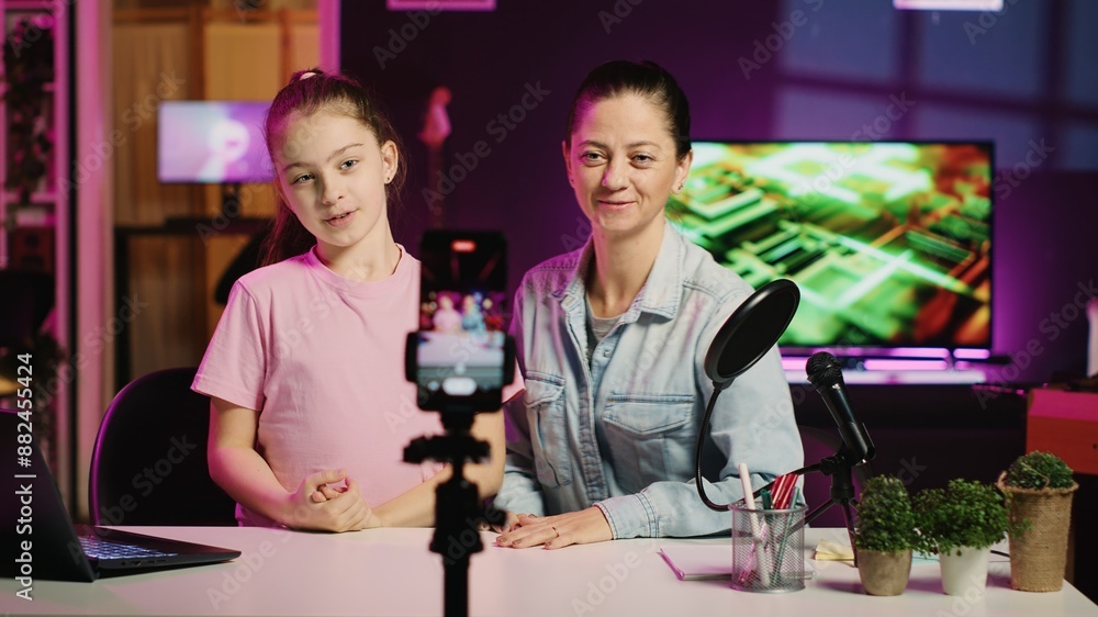 Happy child and mom filming reaction video for gen Z viewers, preparing to look at online videos on laptop. Little girl and her mother recording reaction to internet clips for family channel Happy child and mom filming reaction video for gen Z viewers, preparing to look at online videos on laptop. Little girl and her mother recording reaction to internet clips for family channel