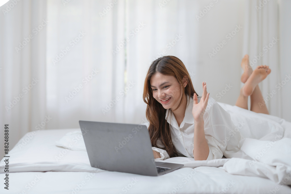 Young woman happily works from home in her cozy bedroom, using her laptop for a video call, embracing online communication Young woman happily works from home in her cozy bedroom, using her laptop for a video call, embracing online communication