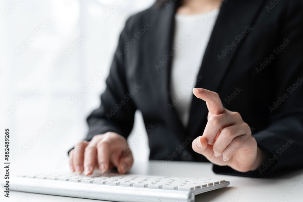Confident businesswoman typing on keyboard, pointing, in office. Modern leader in black suit, analyzing data with natural light. Global business expert Confident businesswoman typing on keyboard, pointing, in office. Modern leader in black suit, analyzing data with natural light. Global business expert