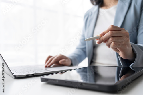 Businesswoman is working on a project using a laptop and a graphic tablet with a stylus pen, indicating a creative and digital workflow photo