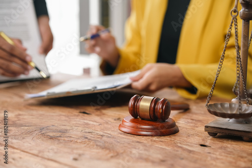 Lawyer advises a client signing a legal document in a business office, discussing law and justice. The lawyer holds a pen, guiding the client