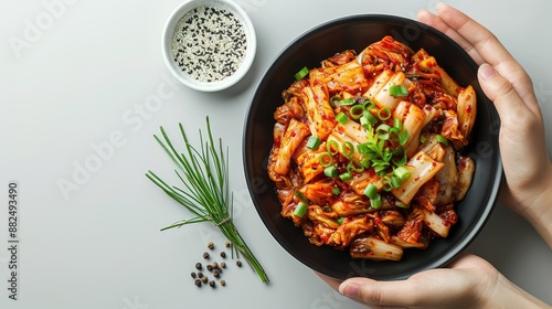 Kimchi korean food with accompaniments in a black bowl with hand, looks delicious on a clean white background