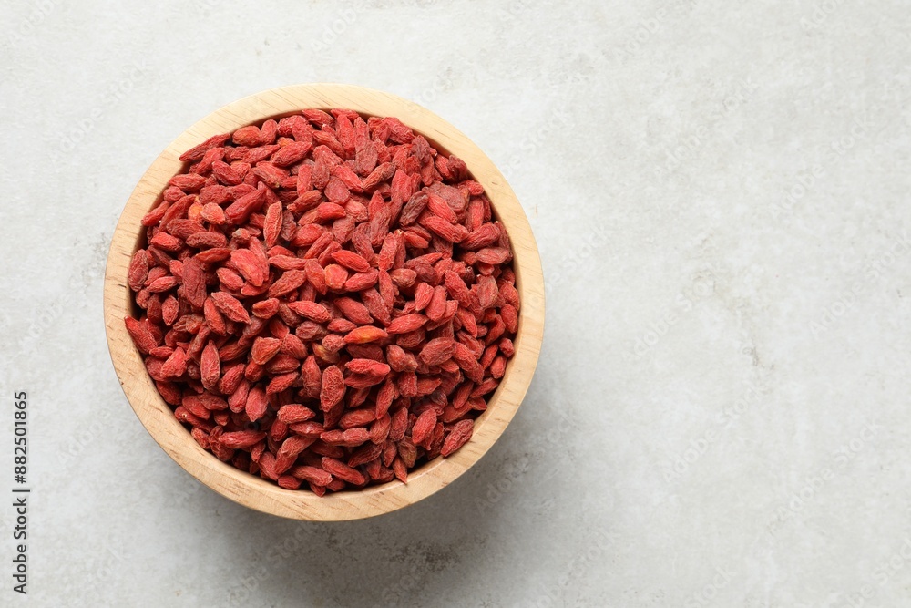 Dried goji berries in bowl on light textured table, top view. Space for text Dried goji berries in bowl on light textured table, top view. Space for text
