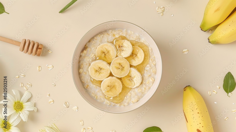 A flat lay featuring a bowl of oatmeal with sliced bananas and a drizzle of honey on a light beige background A flat lay featuring a bowl of oatmeal with sliced bananas and a drizzle of honey on a light beige background