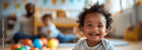 Happy Black Toddler Playing with Toys in Nursery Room at Daycare Center with Parents in Background