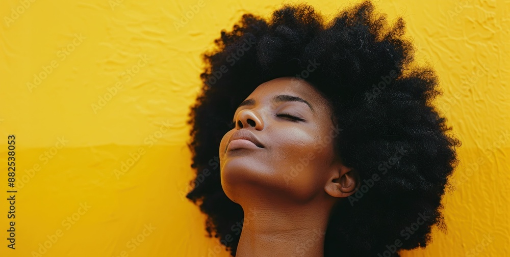 African american woman with afro hair standing in front of vibrant yellow wall as a fashion statement African american woman with afro hair standing in front of vibrant yellow wall as a fashion statement