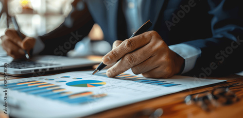 Businessman Analysing Financial Graphs Holding Pen and Working with Documents on Desk in Office Accounting Finance Concept