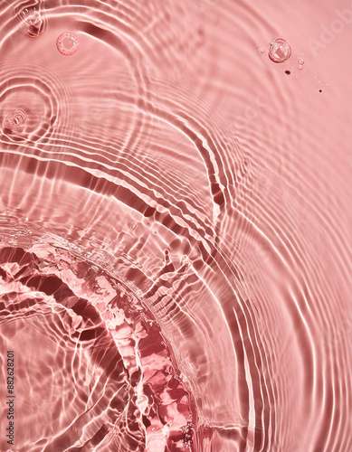 Closeup of pink transparent clear calm water surface texture with splashes and bubbles. Trendy abstract summer nature background. Coral colored waves in sunlight. photo