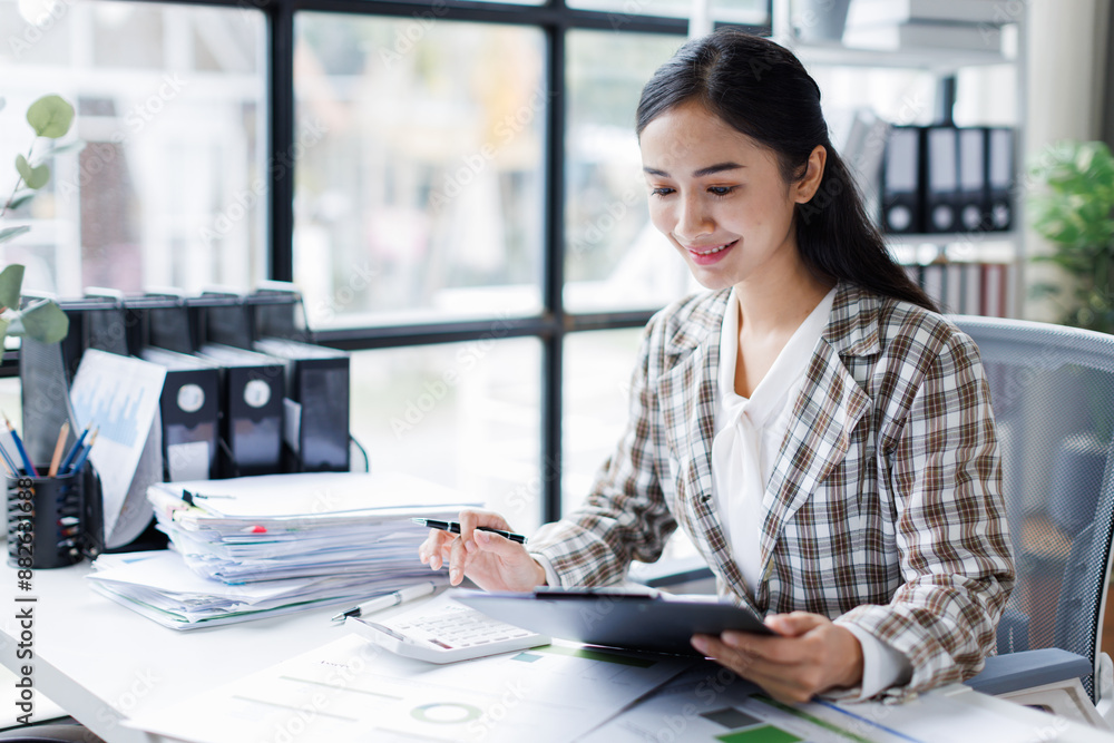 Asian Business woman using calculator and laptop for doing math finance call phone on an office desk, tax, report, accounting, statistics, and analytical research concept