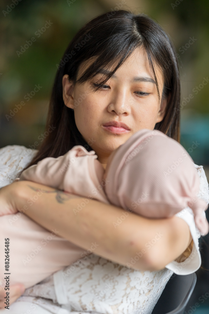 A twenty-something Malaysian woman holding a few-months-old baby at a stylish cafe in Selangor, Malaysia, on a sunny early summer afternoon. A twenty-something Malaysian woman holding a few-months-old baby at a stylish cafe in Selangor, Malaysia, on a sunny early summer afternoon.