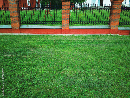 Fresh green summer grass next to the brick fence background