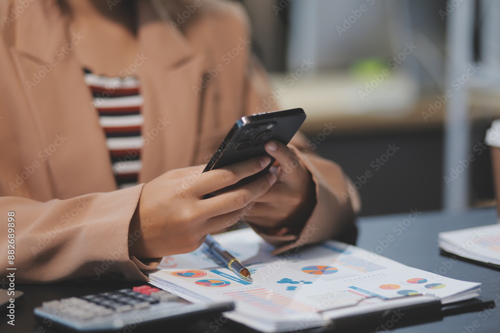 Fototapeta premium Young beautiful Asian businesswoman holding smartphone while working in the office room.