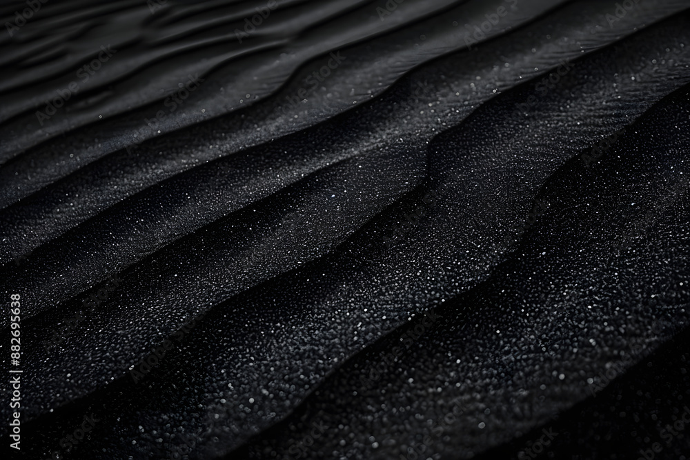 Fototapeta premium Black Sand dune. Black Sand beach macro photography. Background, texture, wave pattern of oceanic sand on the beach, black. Texture of beach sand. Black beach.