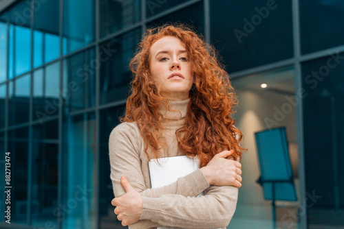 Young Woman With Red Curly Hair Standing Outside Modern Building