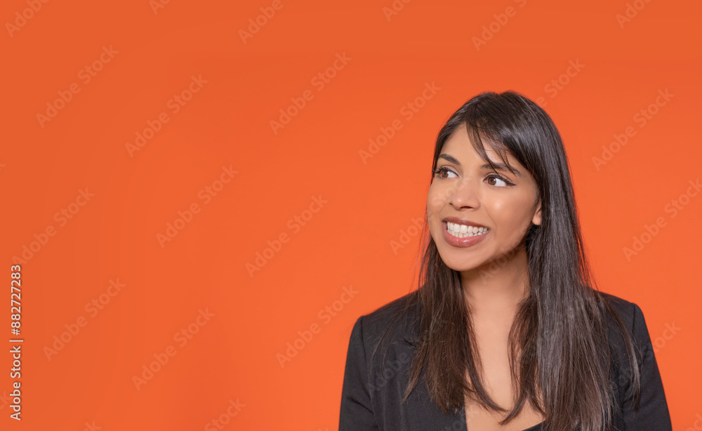Smiling Indian Woman Looking Off Camera Against Orange Background Smiling Indian Woman Looking Off Camera Against Orange Background