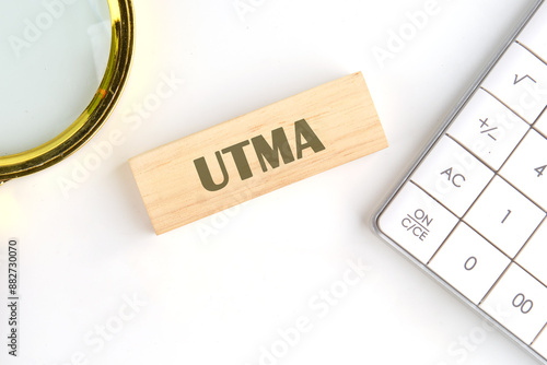 Business concept. UTMA word on wooden blocks in a composition with a magnifying glass and a calculator photo