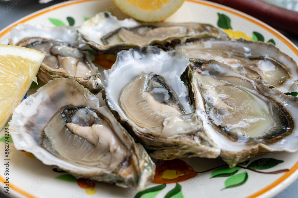 Plate with fresh live oysters with citron, bread, butter and white wine served at restaurant in oyster-farming village, Arcachon bay, Gujan-Mestras port, France Plate with fresh live oysters with citron, bread, butter and white wine served at restaurant in oyster-farming village, Arcachon bay, Gujan-Mestras port, France