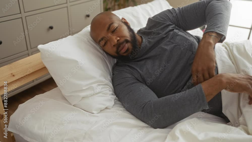 Handsome man lying on bed in a cozy bedroom setting, displaying relaxation and peace as he wakes up in the comfort of his home interior. Handsome man lying on bed in a cozy bedroom setting, displaying relaxation and peace as he wakes up in the comfort of his home interior.