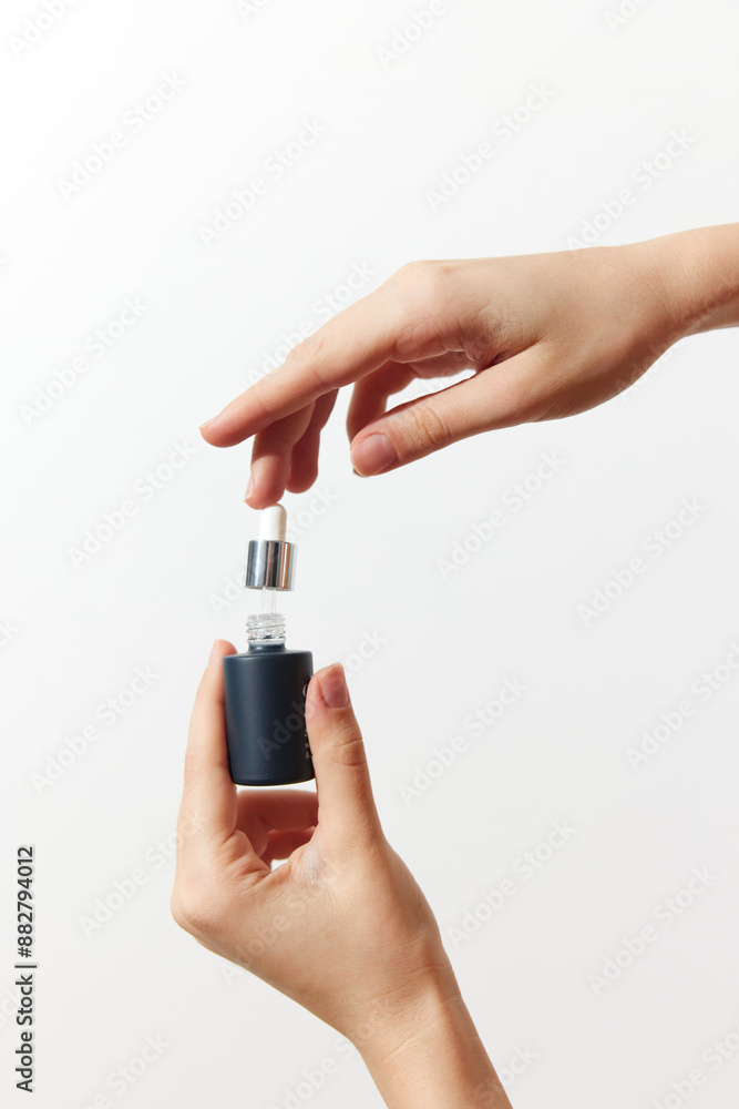 Two hands holding a small bottle of perfume on a white background Two hands holding a small bottle of perfume on a white background