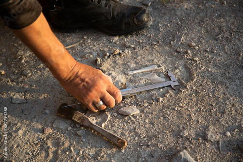 An archaeologist measures a found artifact in the form of bones. Historical reconstruction of archaeological research of the 19th century