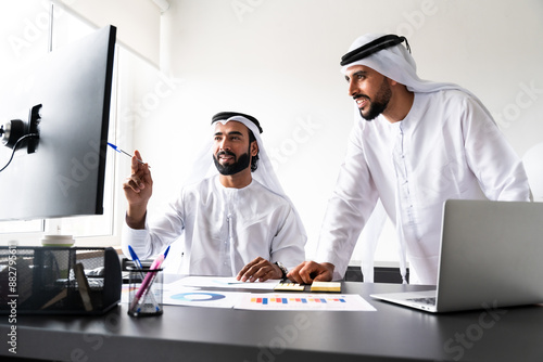 Arab men wearing traditional emirate clothing  working in the office - Middle eastern businessmen brainstorming at work