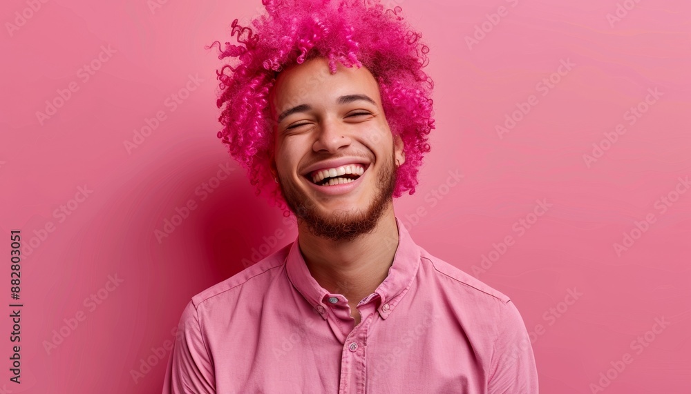 Cheerful Young Man with Curly Pink Hair in Shiny Pink Shirt, Solid Bright Pink Background Cheerful Young Man with Curly Pink Hair in Shiny Pink Shirt, Solid Bright Pink Background