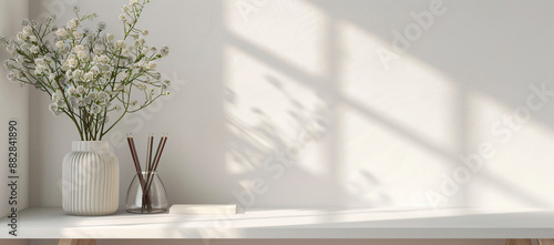 Fototapeta Naklejka Na Ścianę i Meble -  cottagecore style home office interior, white wall background, copy space for text, minimalistic spring decor with flowers in vase and pencils on table, banner mockup,