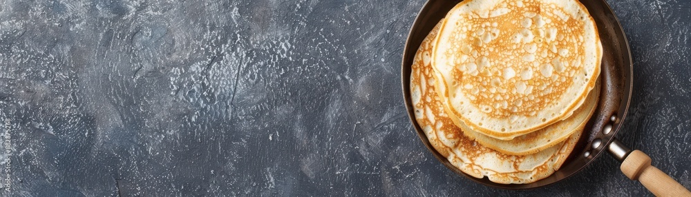 Top view of delicious golden pancakes in a skillet on a dark textured background, perfect for breakfast or brunch themes. Top view of delicious golden pancakes in a skillet on a dark textured background, perfect for breakfast or brunch themes.