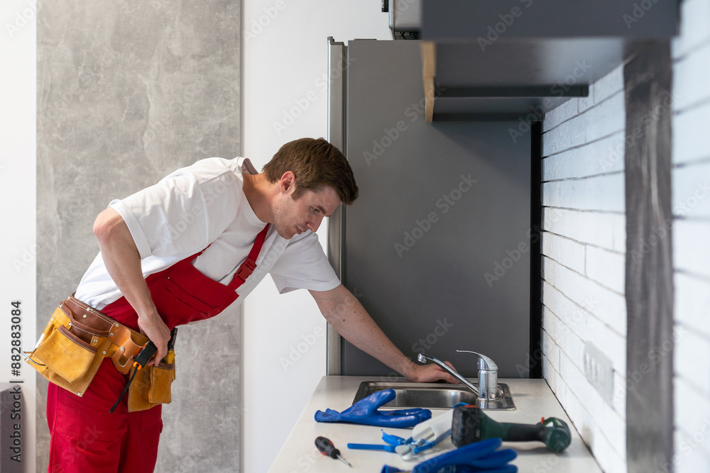 Young Repairman Installing Faucet Of Kitchen Sink In Kitchen Room Young Repairman Installing Faucet Of Kitchen Sink In Kitchen Room