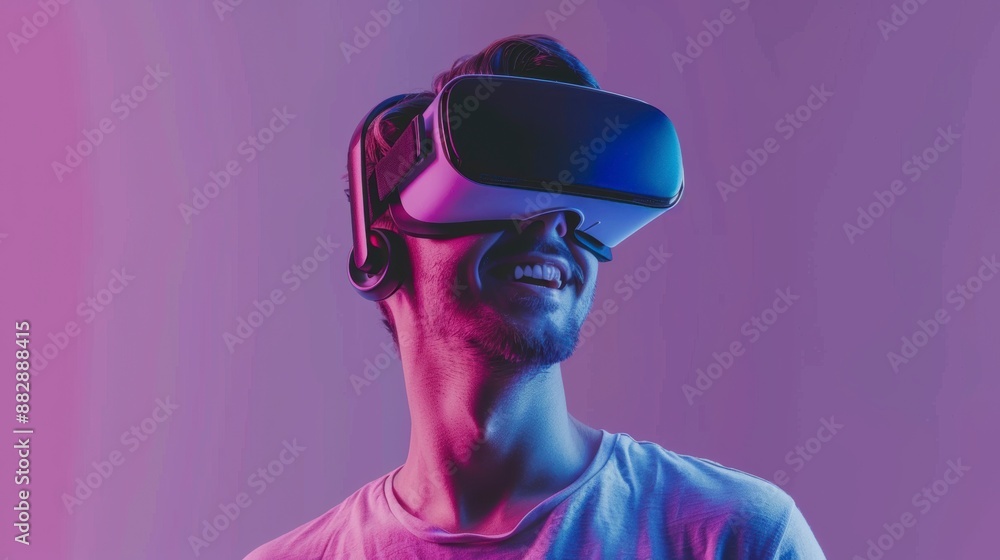 Joyful young man in a VR headset, exploring virtual worlds against a bright solid purple background with copy space Joyful young man in a VR headset, exploring virtual worlds against a bright solid purple background with copy space