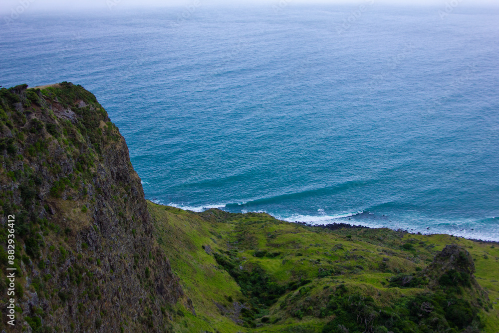 Narrow promontory rising high above over calm blue waters of Tasman Sea. Te Toto Gorge Lookout, Raglan, New Zealand Narrow promontory rising high above over calm blue waters of Tasman Sea. Te Toto Gorge Lookout, Raglan, New Zealand