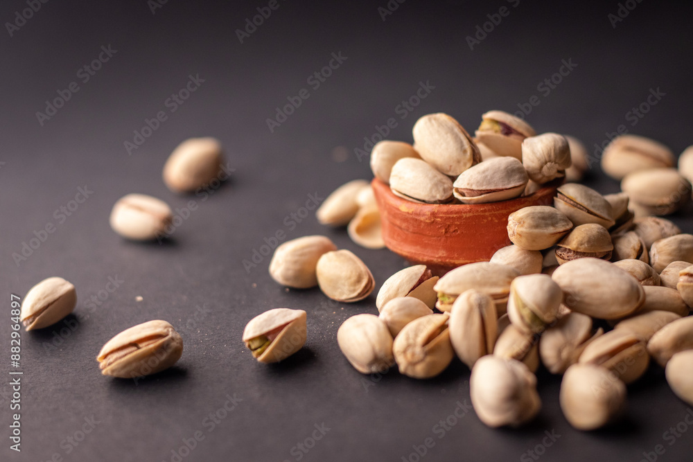 Pistachio nuts kept in a clay pot on a dark grey background with a space for text on the left Pistachio nuts kept in a clay pot on a dark grey background with a space for text on the left