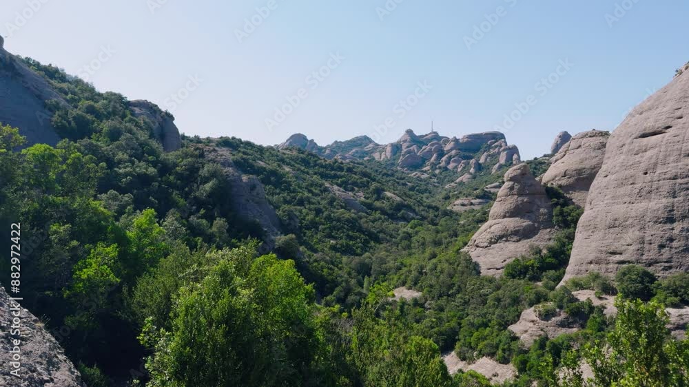 Walking in the mountains of Montserrat in Spain in summer. Panorama of mountain peaks and green plants against the blue sky. Trails for active recreation Walking in the mountains of Montserrat in Spain in summer. Panorama of mountain peaks and green plants against the blue sky. Trails for active recreation