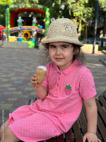 Portrait of a cute brunette girl with ice cream in her hand on a walk in the park. 