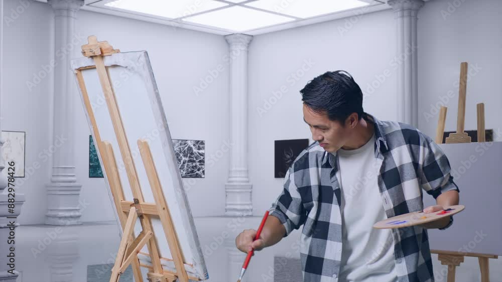 Asian Male Artist Painting On Canvas By Oil Paints And Brush In Gallery Asian Male Artist Painting On Canvas By Oil Paints And Brush In Gallery