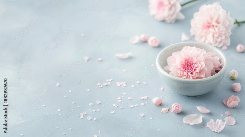 Delicate pink flowers and petals arranged on a light blue background, with a small bowl holding one flower. Perfect for spa or relaxation themes. Delicate pink flowers and petals arranged on a light blue background, with a small bowl holding one flower. Perfect for spa or relaxation themes.