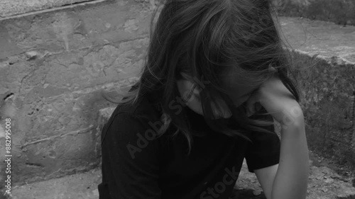 A sad lonely girl sits alone on the steps. Concept of loneliness, loss of a loved one ,bullying, mental health problems in bullies and teenagers photo