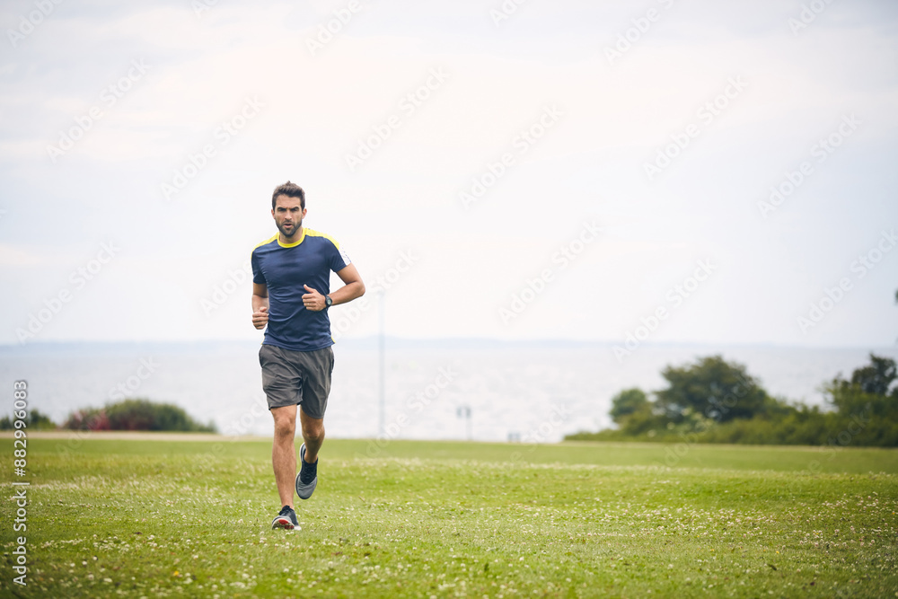Outdoor, fitness and man on field for running challenge, wellness and healthy morning exercise. Training, cardio and runner on grass in nature with commitment, progress and athlete in muscle workout. Outdoor, fitness and man on field for running challenge, wellness and healthy morning exercise. Training, cardio and runner on grass in nature with commitment, progress and athlete in muscle workout.