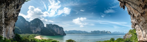 Panoramic view of a tropical beach from a cliffside cave with clear blue skies, dramatic rock formations, and lush green vegetation.
