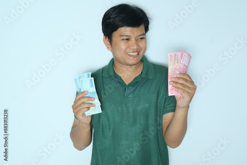 Young Asian man showing smiling happy expression while giving money to someone. Wearing a green t-shirt photo