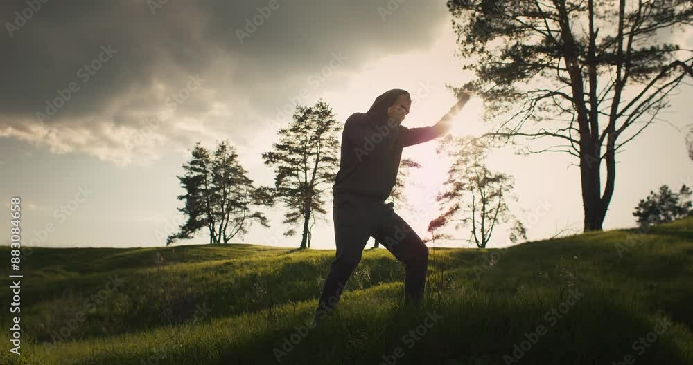 Young boxer man training in the mountains. Boxing outside training. Shadow boxing in sunset light Young boxer man training in the mountains. Boxing outside training. Shadow boxing in sunset light