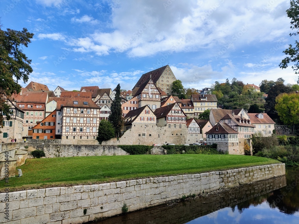 Fototapeta premium Cityscape of a swabian city in south germany with green grass, a river, cloudy sky and half-timbered houses