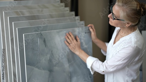 Foto Mature woman with her hand touching a sample of marble stone for flooring and countertops in a design center store for a home renovation redecorating project