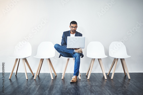 Waiting room, businessman and laptop for recruitment, interview and research information for hr questions. Wall background, male candidate and digital for planning, opportunity and reading portfolio