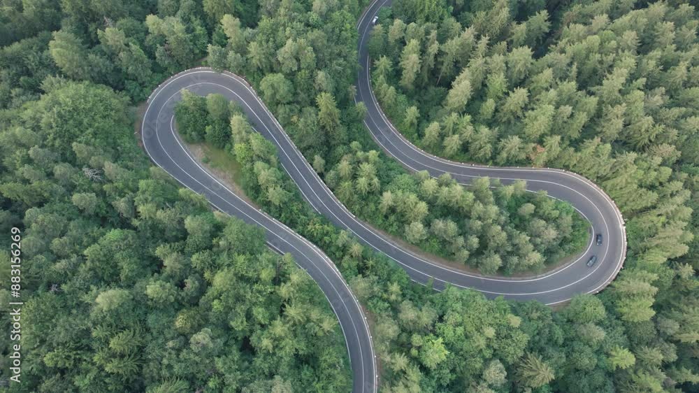 Aerial view of scenic winding mountain road cutting through the green forest Aerial view of scenic winding mountain road cutting through the green forest