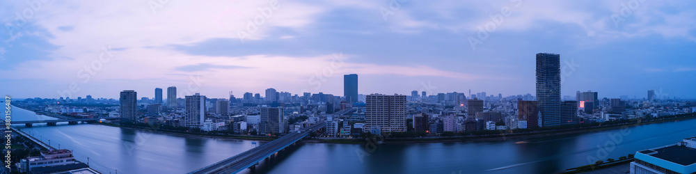Obraz premium Wide panoramic photo of the city on the river, against the blue sky
