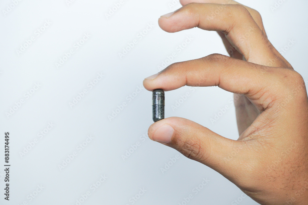 a man holding Nigella sativa oil in a pill (black cumin, also known as habbatussauda). a man holding Nigella sativa oil in a pill (black cumin, also known as habbatussauda).