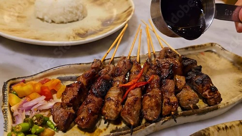 Beef Satay marinated with spice and sweet soy sauce, locals called it Satay Maranggi coriander beef satay, served on plate with onion, chilli, soy sauce and tomato. Indonesian food